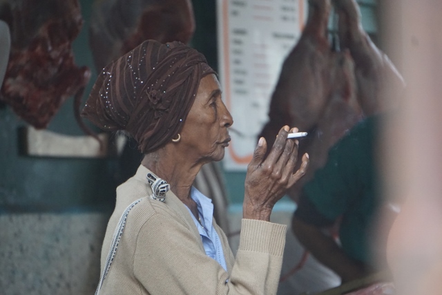 Old Cuban woman in profile holding a cigarette. 